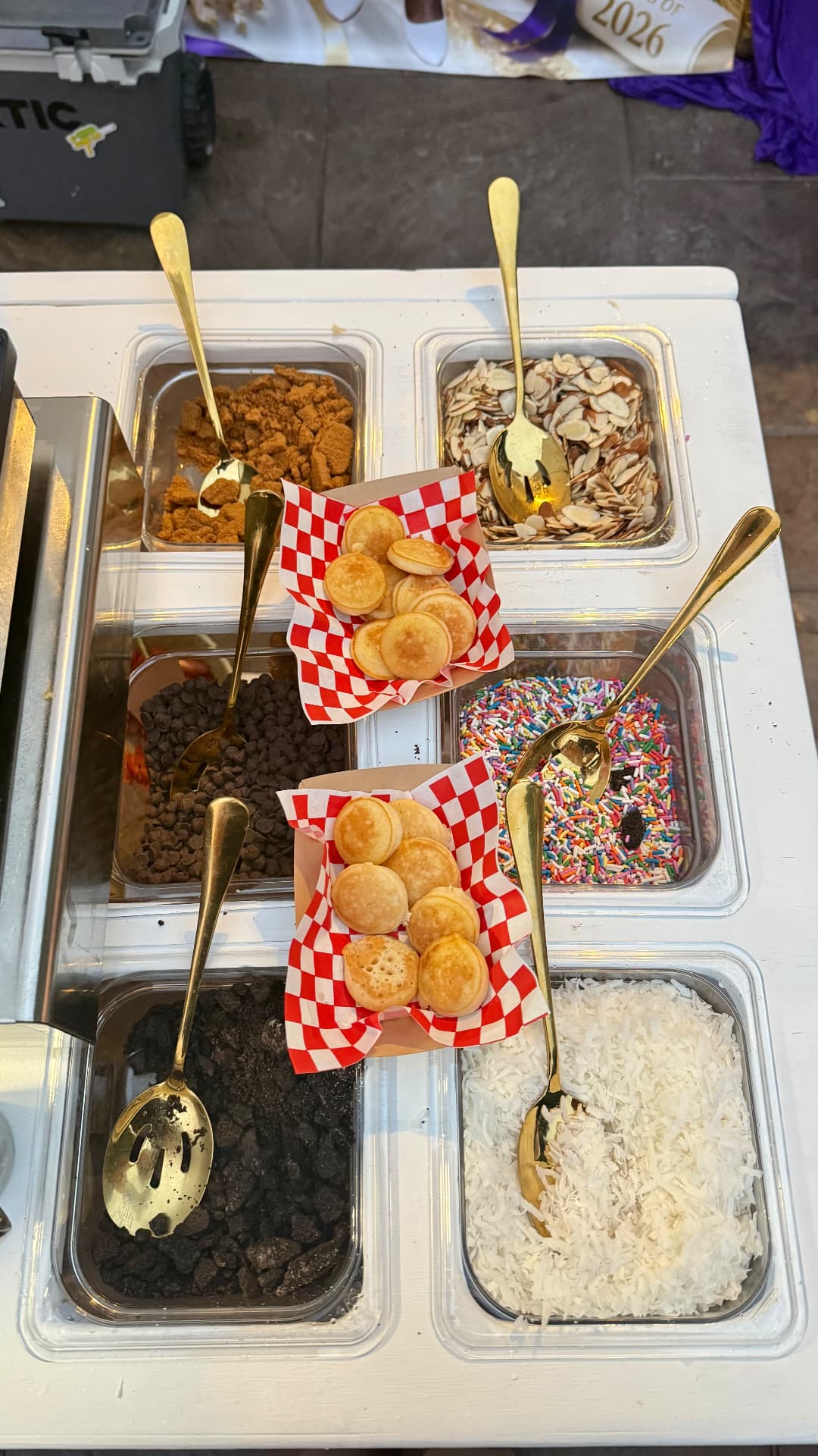 Mini pancakes in checkered boats surrounded by topping trays