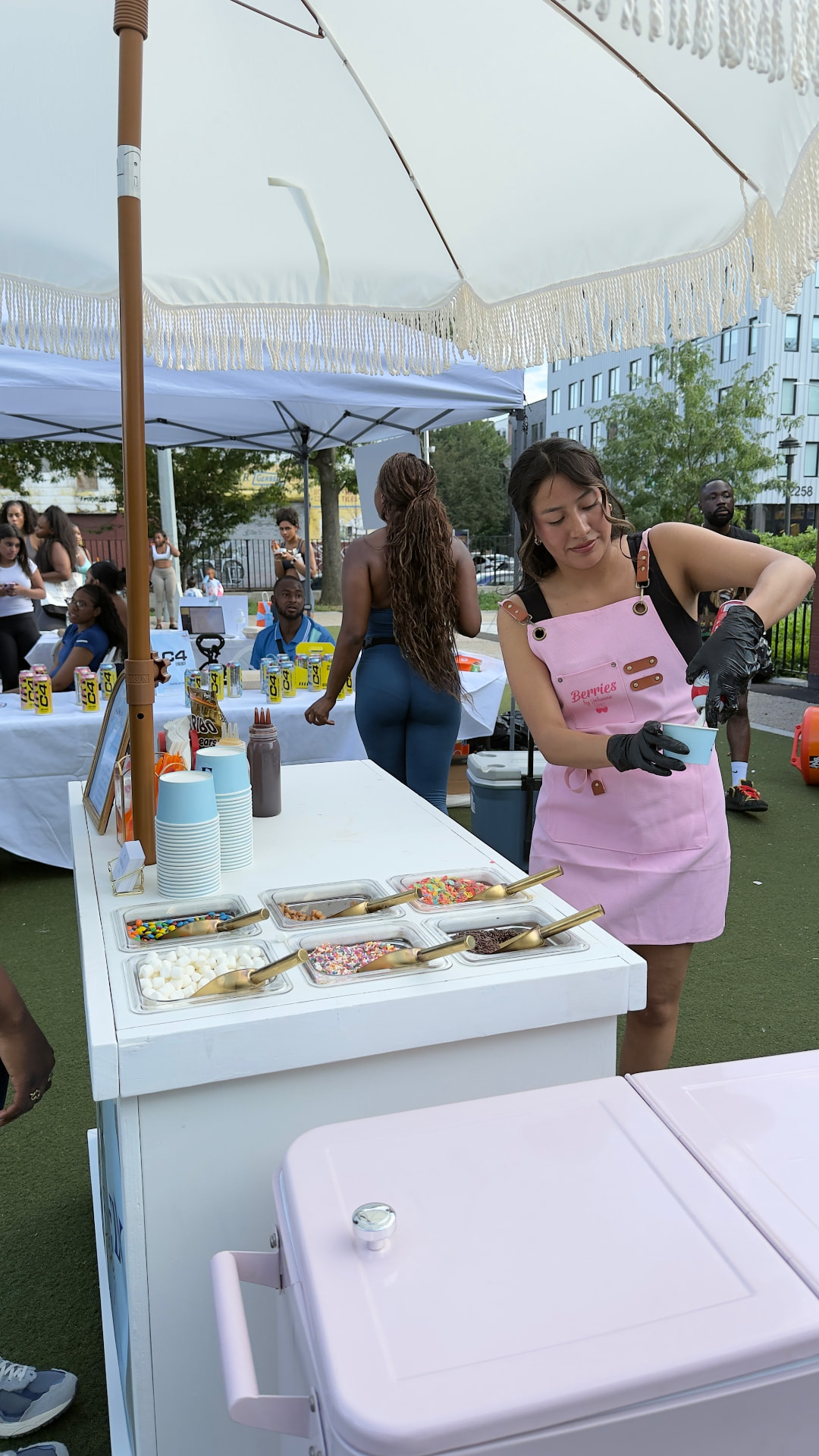 Johanna serving ice cream at the topping cart during an outdoor event