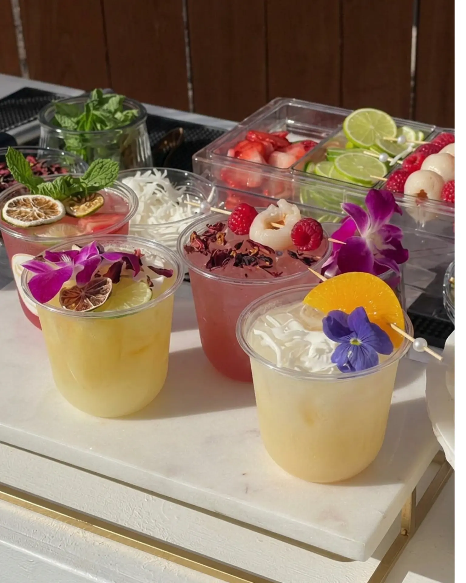 Fresh mocktails with edible flowers, citrus and berries on a styled bar