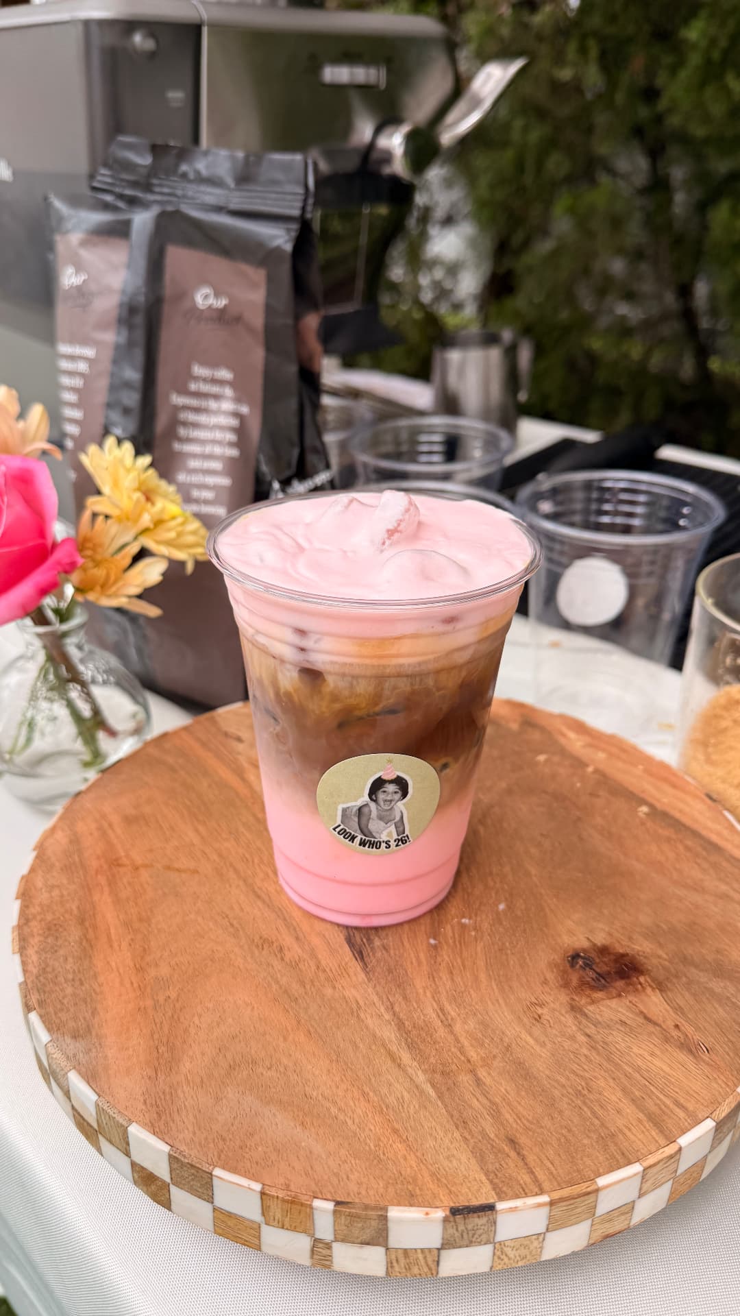 Iced pink coffee drink in a branded cup served on a wooden board