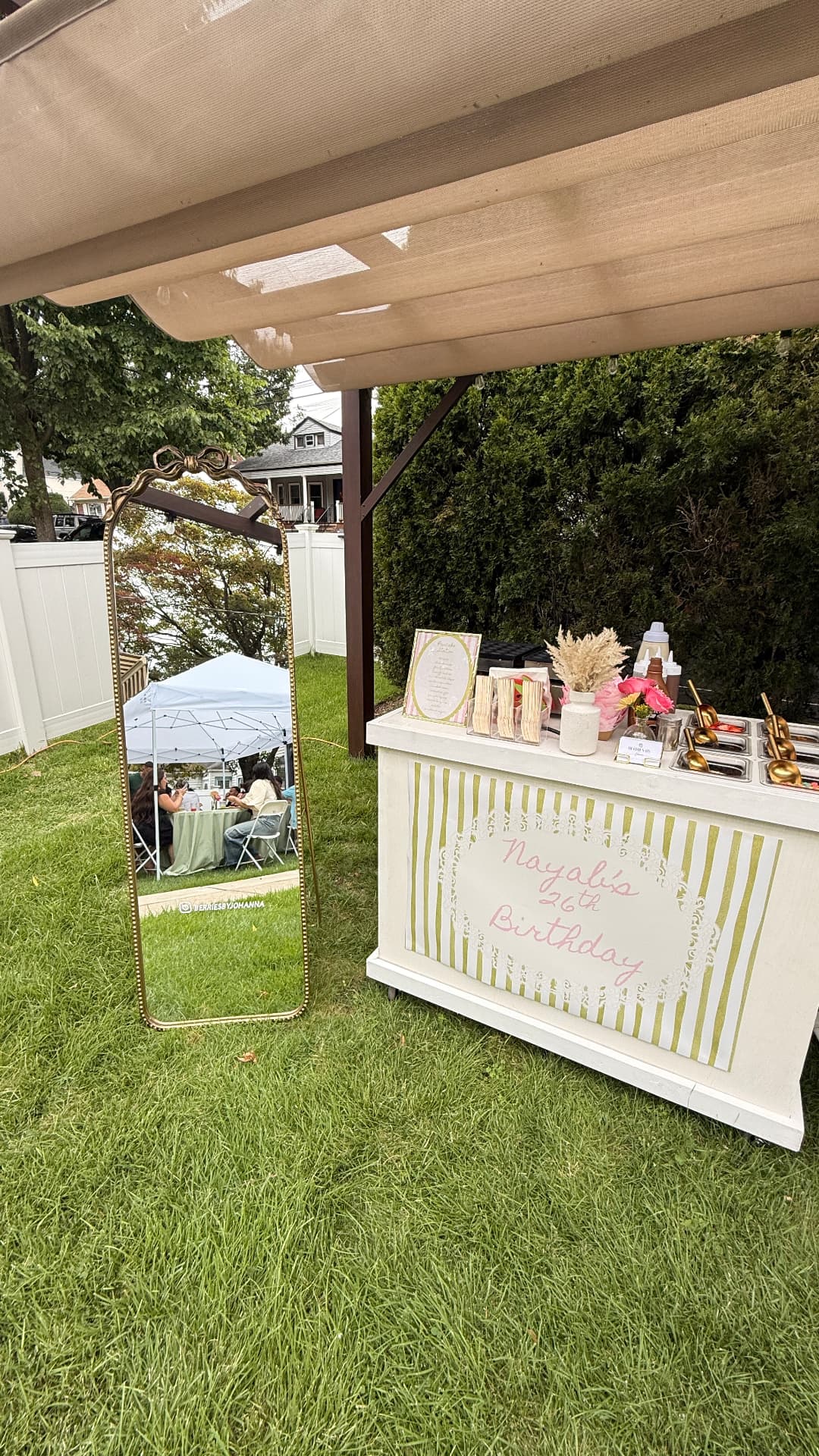 Wide view of the birthday dessert cart setup under a tent with a decorative mirror